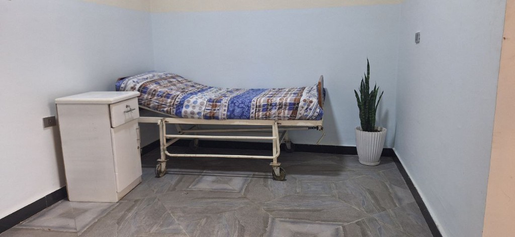 Patient room with bed and bedside cabinet at Enat Nursing Home